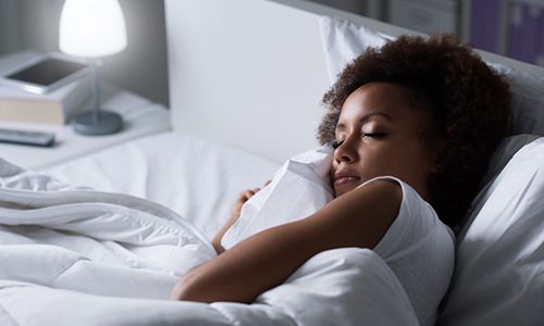 Woman enjoying a great night’s sleep in all white bed