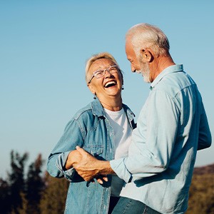 Man and woman with white hair in denim shirts outside smiling