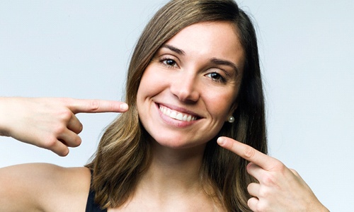 Woman pointing to her teeth after fixing bite alignment
