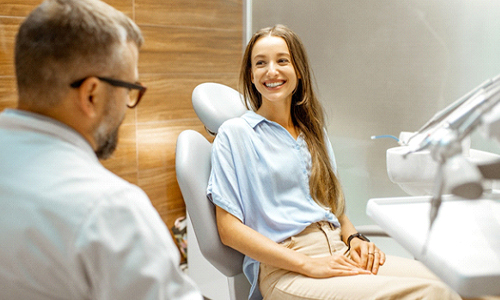 A dentist talking to a young female patient about the possibility of receiving treatment with Invisalign