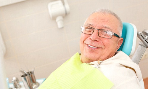older man glasses smiling in dentist chair