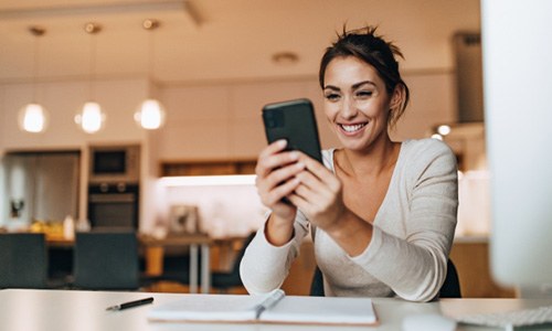 a woman smiling and looking at her phone 