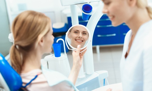 A female patient admiring her smile in the mirror