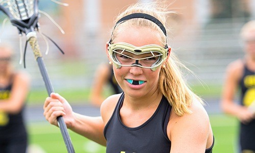 Teen girl with mouthguard playing lacrosse