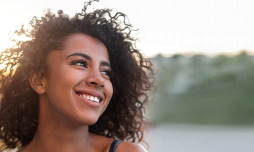 A young woman outside and smiling to show off her smile makeover in Tysons