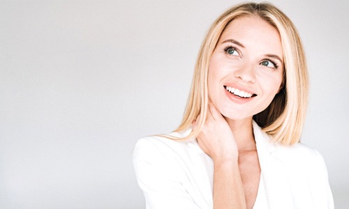 A young woman with blonde hair wearing a white blazer and smiling 