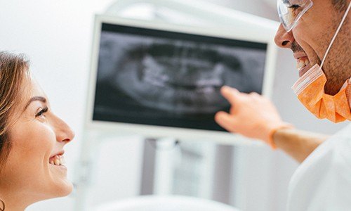 Smiling patient and dentist looking at x-rays