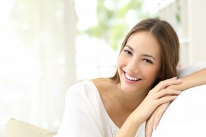 Smiling woman wearing white on a white couch